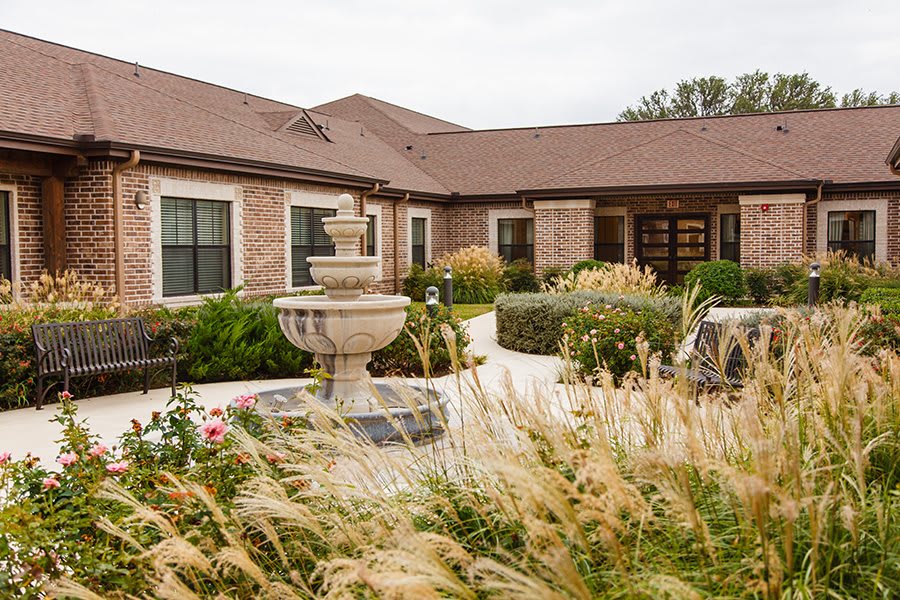A charming house with well-maintained landscaping and a central fountain.