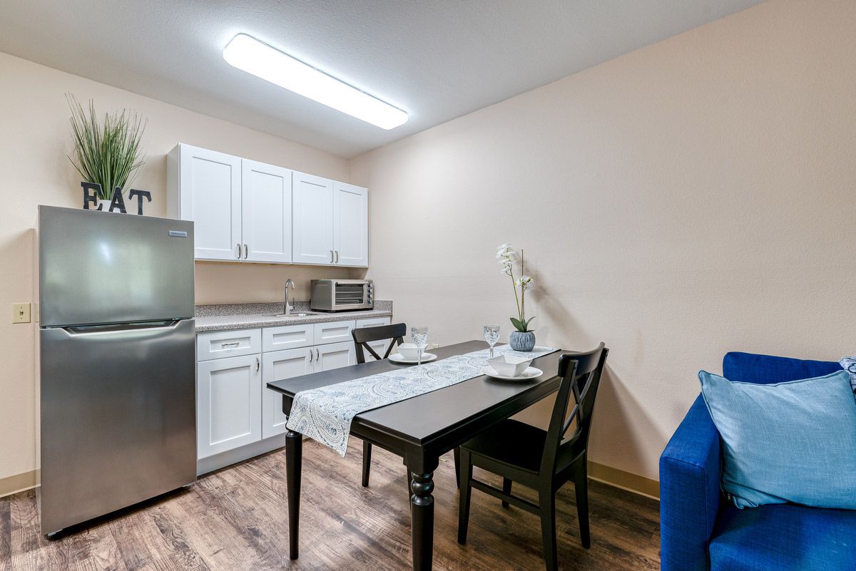 A modern kitchen and dining area with a table, chairs, refrigerator, and microwave.