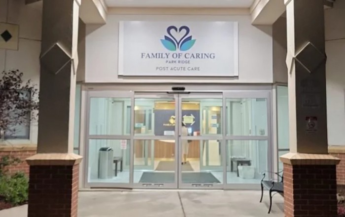 Entrance to a facility with glass doors and a sign that reads 'Family of Caring, Healthcare and Rehabilitation.'