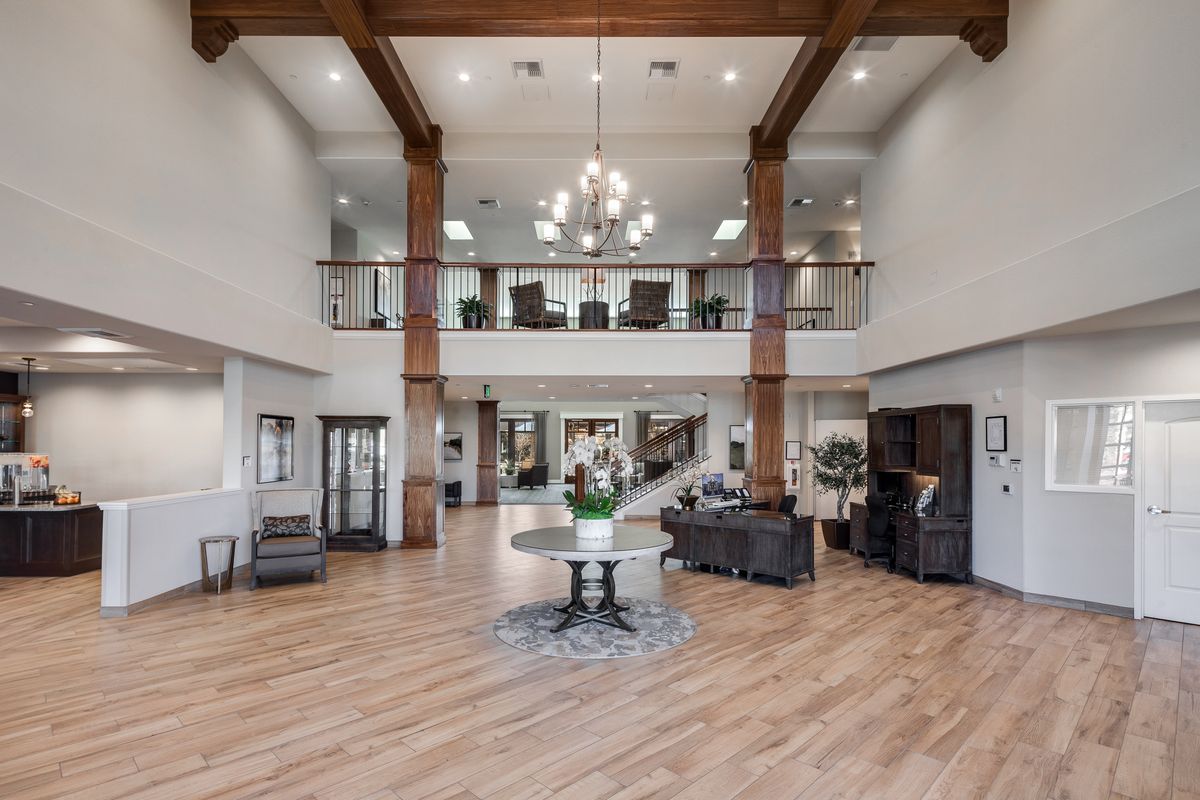 A spacious and modern lobby with a high ceiling, featuring wooden beams and a central chandelier.
