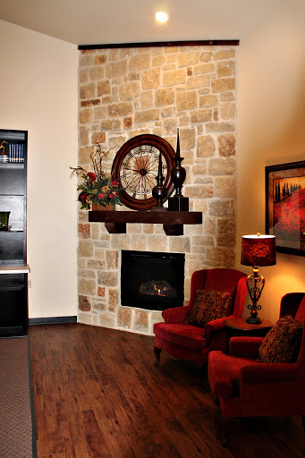 A cozy living room featuring a stylish stone fireplace and comfortable red chairs.