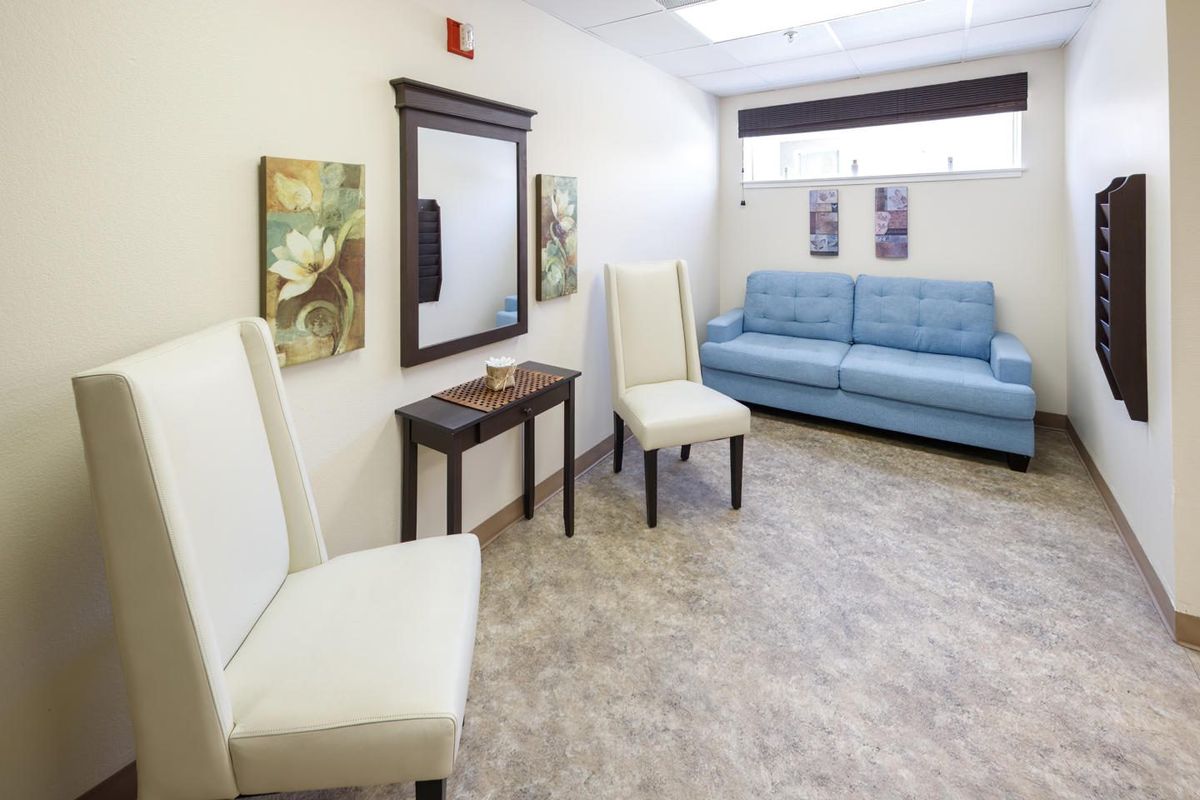 A modern waiting room with white chairs, a blue sofa, and decorative artwork.