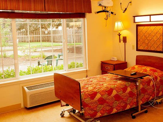 A cozy hospital room with a large window, providing a view of the garden outside.