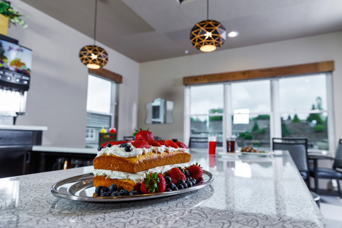 A delicious sponge cake topped with fresh berries sits on a modern kitchen countertop.