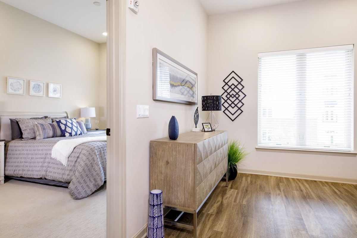 A modern bedroom interior featuring a dresser with decorative items and artwork on the walls.