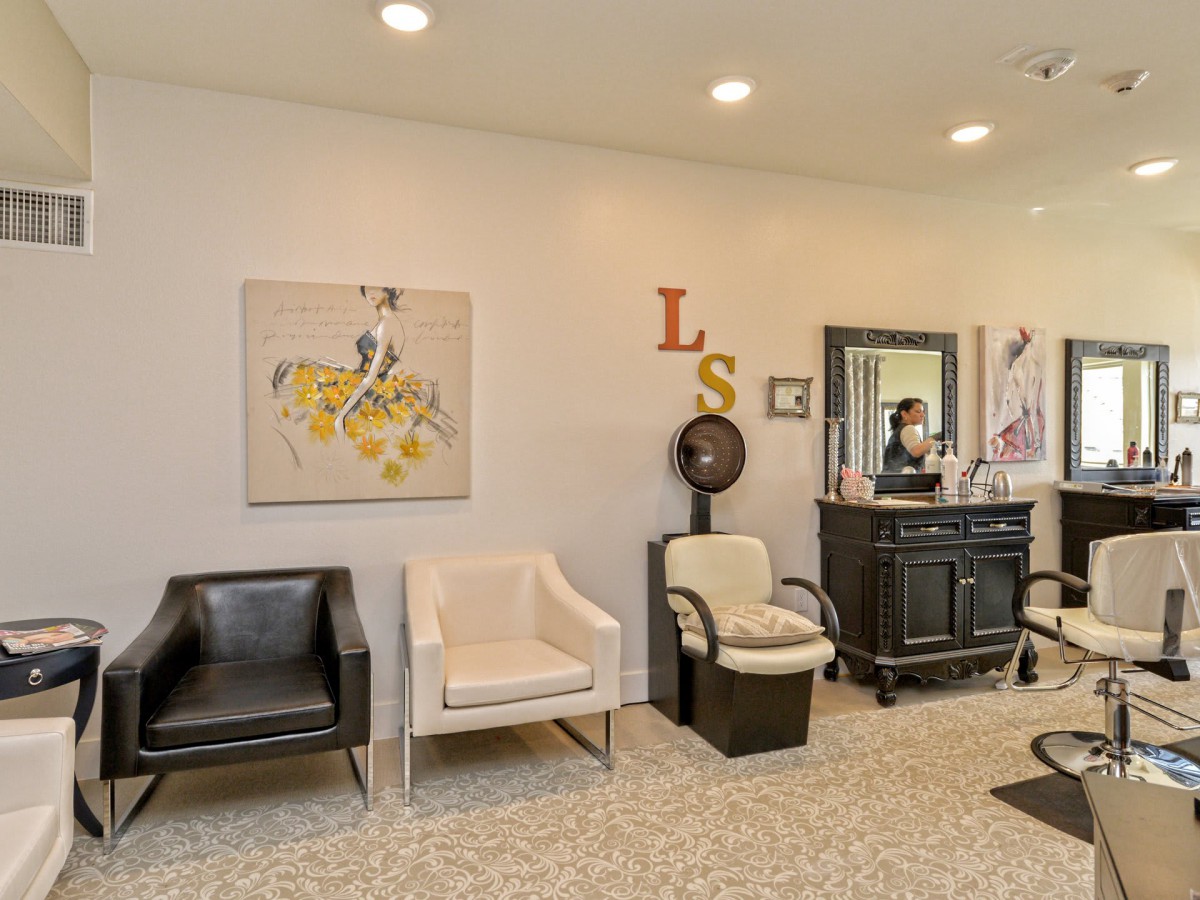 A modern salon interior featuring stylish chairs, wall art, and a large mirror.