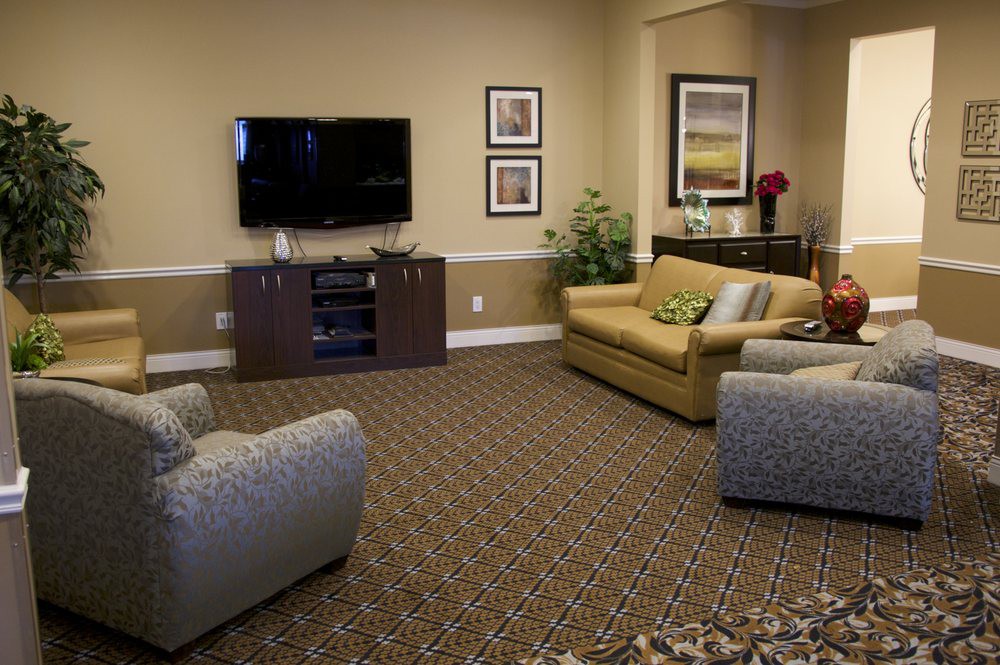 A cozy living room with a television, sofa, armchairs, and decorative elements.