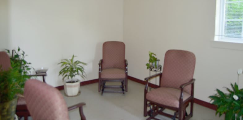 A minimalist waiting room with chairs and potted plants.