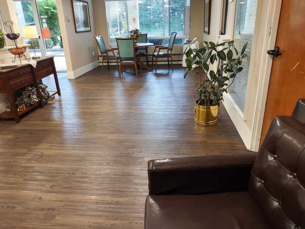 A cozy lobby area with wooden flooring, seating arrangements, and a potted plant by the window.