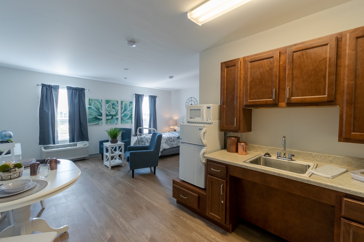 A cozy studio apartment featuring a compact kitchen and a comfortable living area.