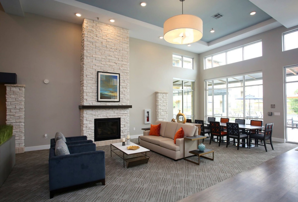 A modern living room with a fireplace, comfortable seating, and natural light from large windows.