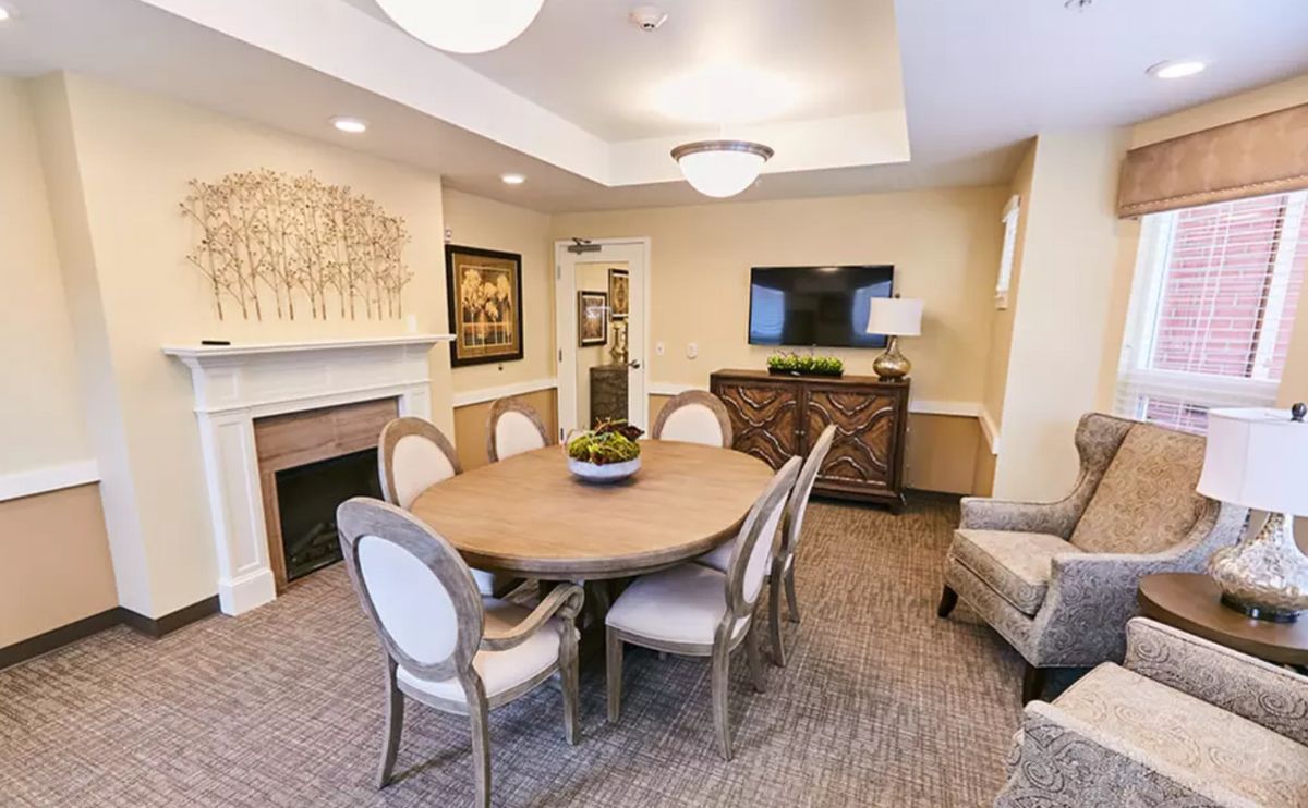 A cozy dining room featuring elegant furniture, a round table, and a warm fireplace.