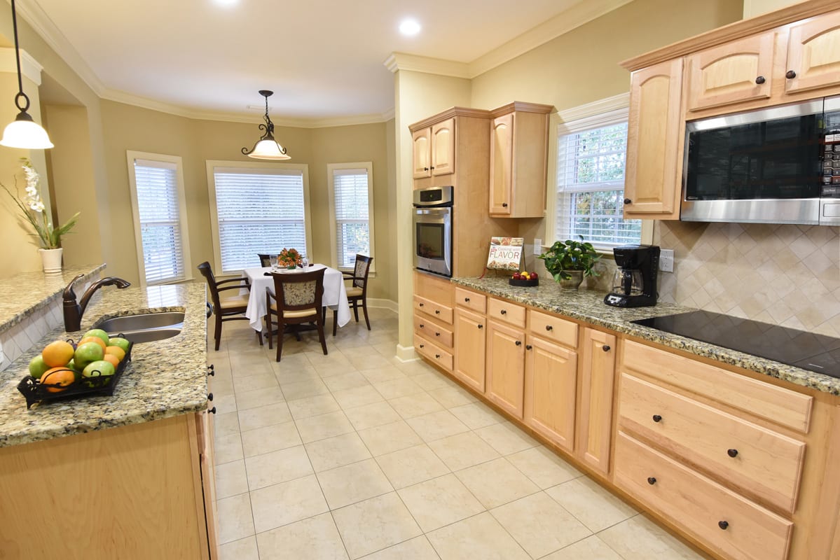 A bright and modern kitchen with wood cabinets, granite countertops, and a cozy dining area.