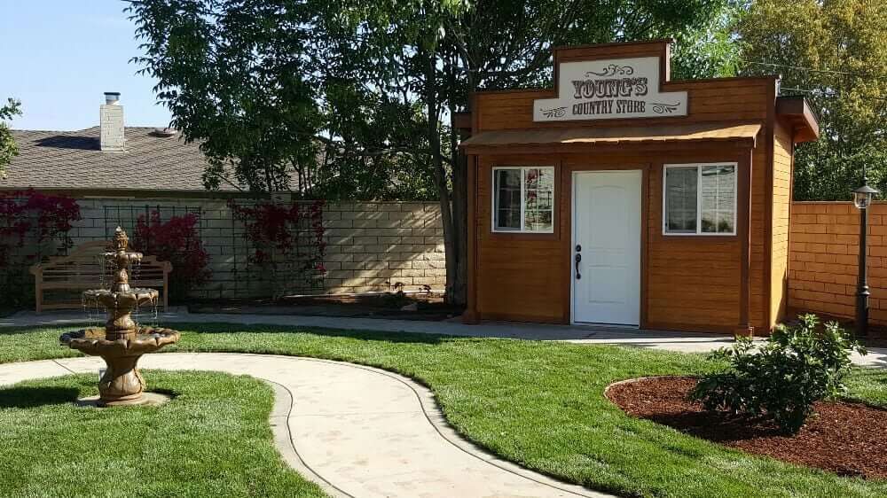 A small wooden building with a pathway in a grassy yard.