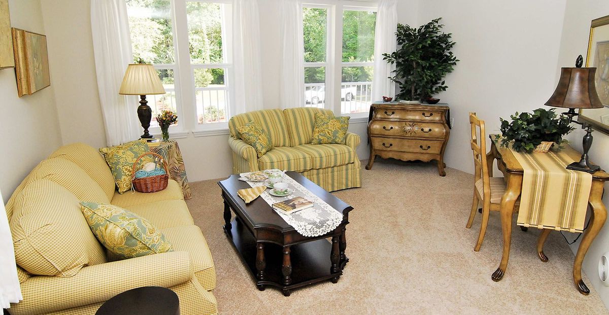 A cozy living room with a striped sofa, armchair, dark wood coffee table, and decorative chest.