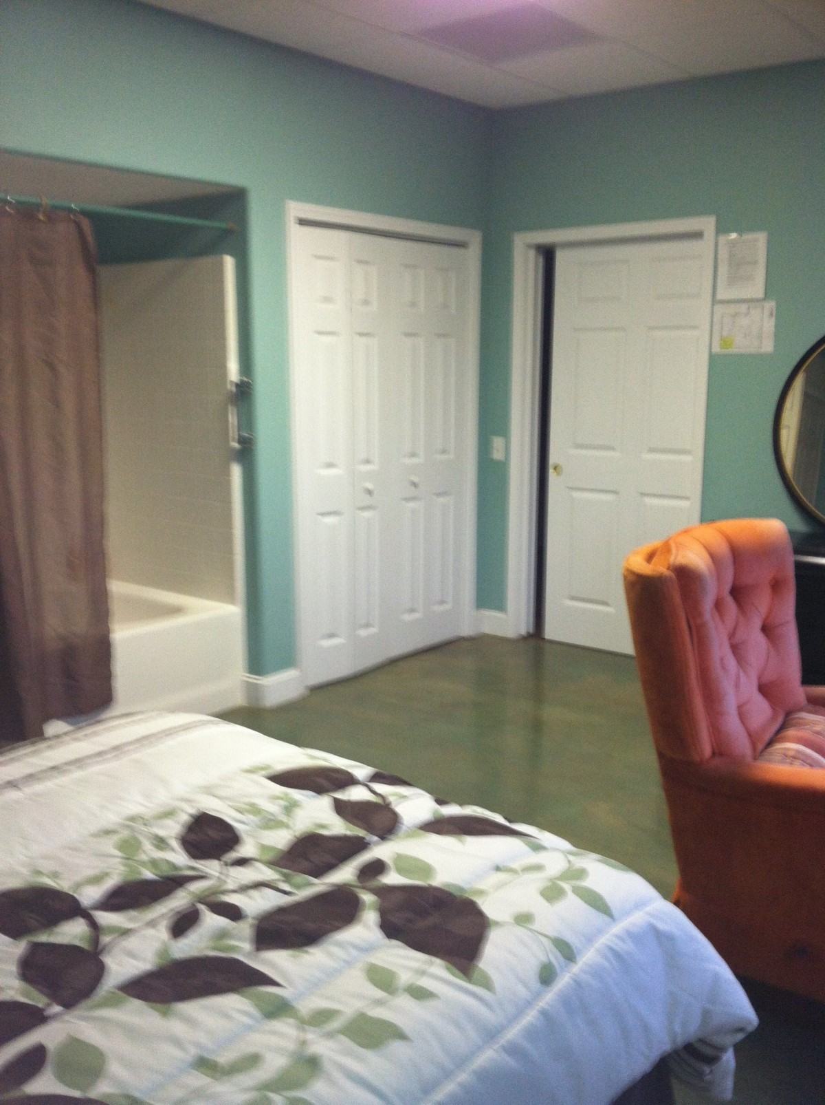 A cozy bedroom with a view of the bathroom, featuring a comfy chair and closet.