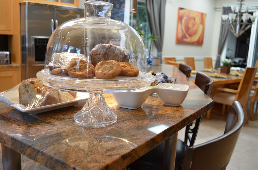 A cozy bakery cafe with pastries displayed under a glass dome on a wooden table.