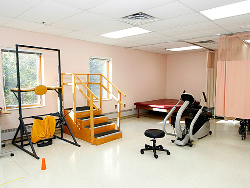 A well-equipped rehabilitation gym featuring various exercise machines and a set of stairs for physical therapy.