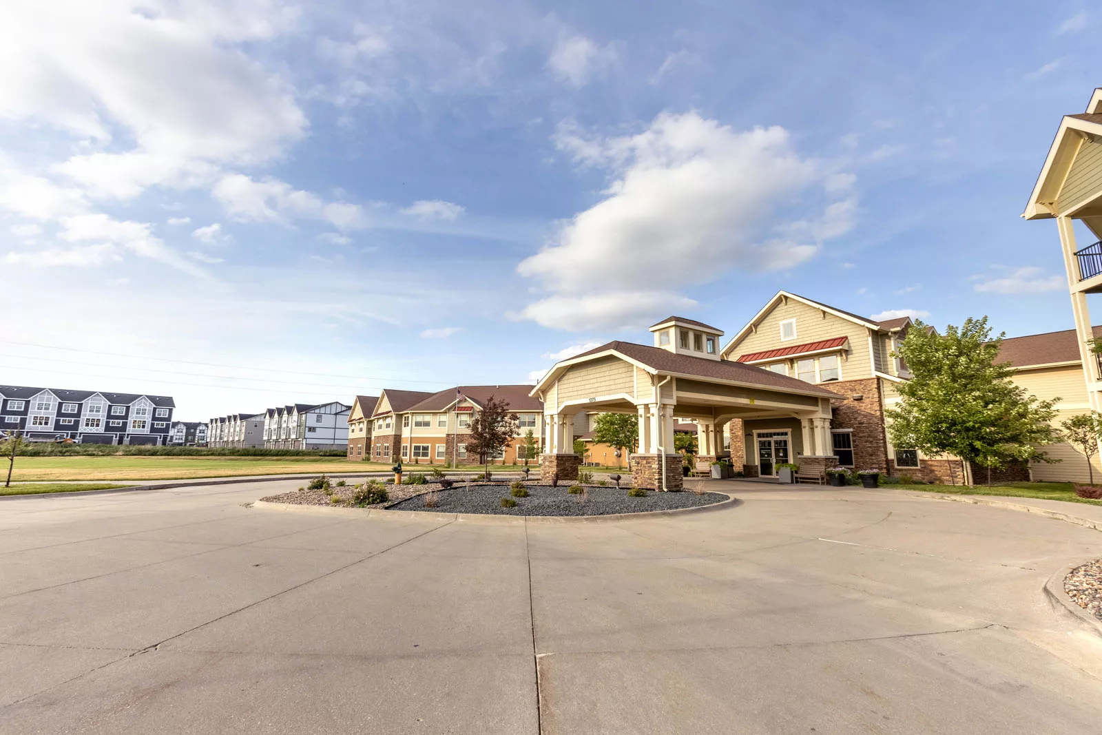 A spacious driveway leads to the entrance of a large building under a partly cloudy sky.