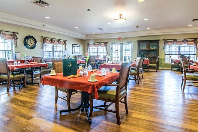 A cozy dining area with tables and chairs set on a wooden floor.