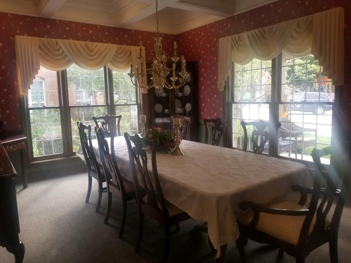A formal dining room with a large table, ornate chandelier, and elegant decor.