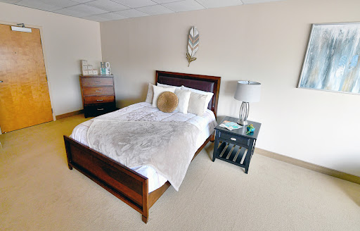 A cozy and modern bedroom featuring a neatly made bed, bedside lamp, and stylish decor.