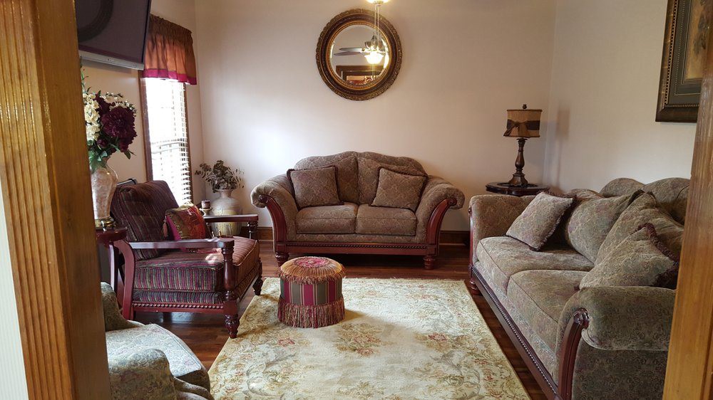 A cozy living room with sofas, an armchair, a mirror, and a lamp.