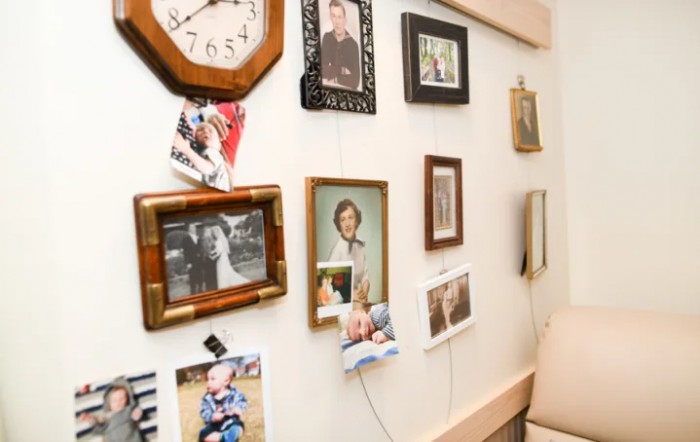 A wall adorned with various framed family photographs and a clock, showcasing personal memories in a cozy home setting.