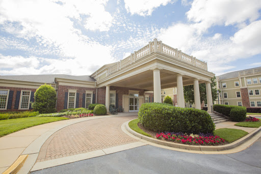A beautifully designed entrance to a building featuring elegant columns and colorful landscaping.
