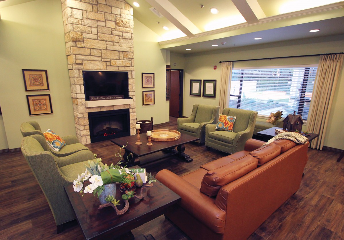 A cozy living room with a stone fireplace, comfortable seating, and a television.