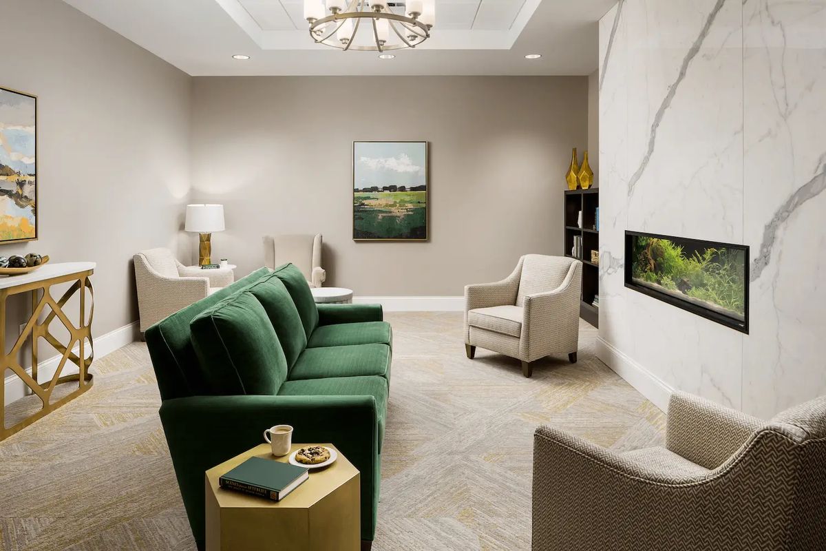A modern living room with a green sofa, a fireplace, and elegant decor.
