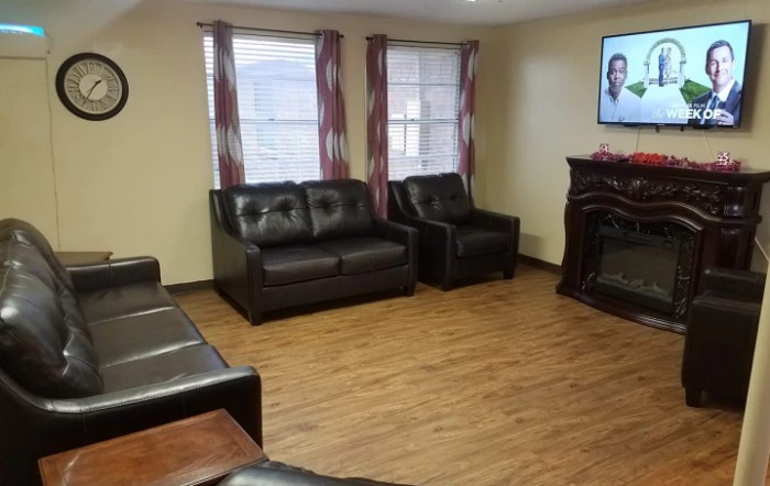 A cozy living room with multiple couches, a television, and windows providing natural light.