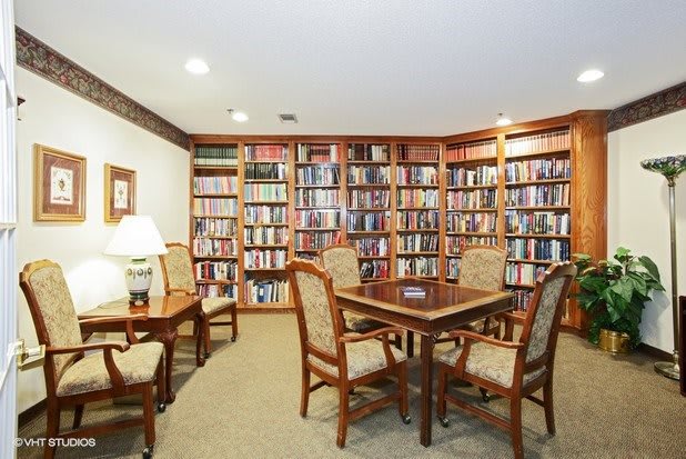 A cozy reading room with bookshelves lining the walls, tables and chairs for studying or relaxing.