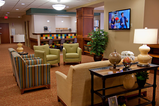 A cozy lobby seating area featuring comfortable chairs, a coffee table, and a television.