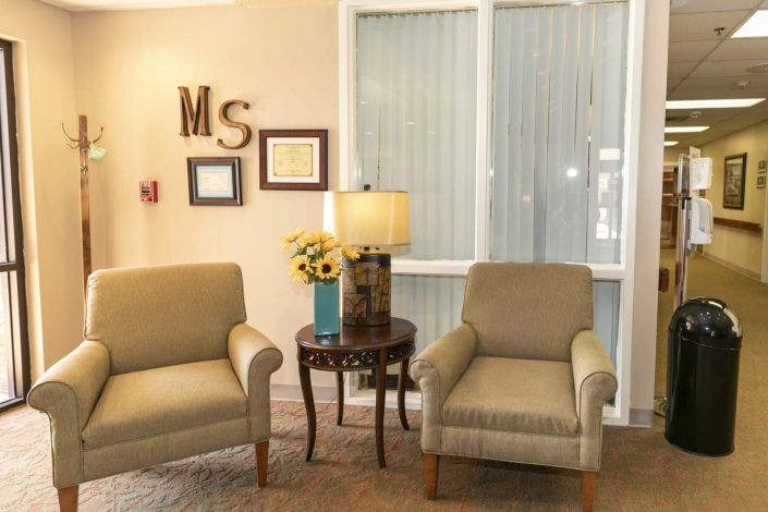 A cozy living room setup with two armchairs, a small round table with a lamp, and decorative elements on the wall.