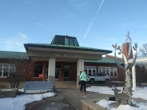 A winter view of a building with snow on the ground and a person approaching the entrance.