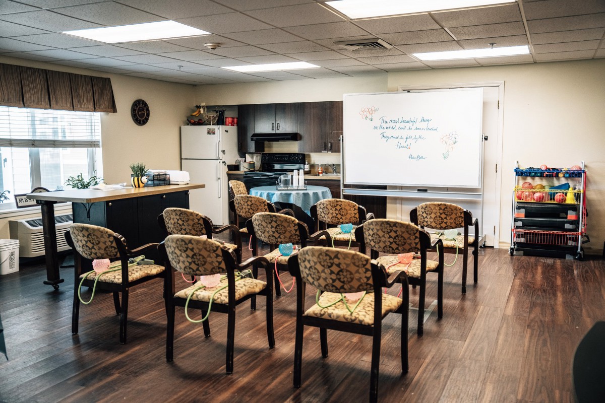 A small room set up with chairs facing a whiteboard, equipped with a kitchenette.