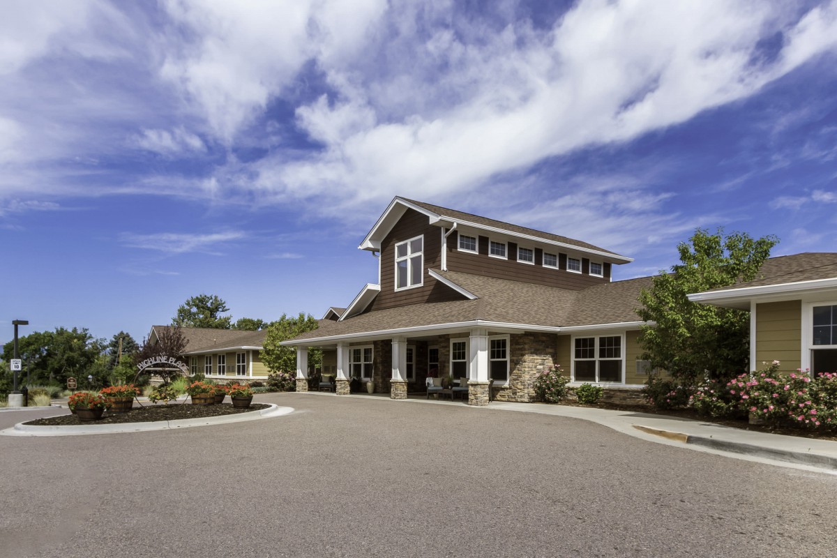 A large house with a porch and gabled roof under a partly cloudy sky.