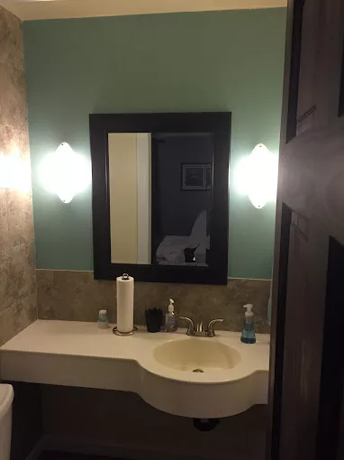 A modern bathroom with a sleek sink, large mirror, and stylish lighting.