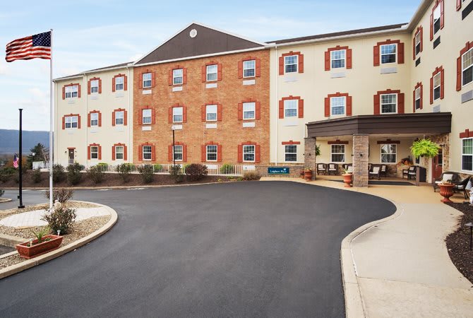 A three-story hotel with a brick facade and an entrance driveway.