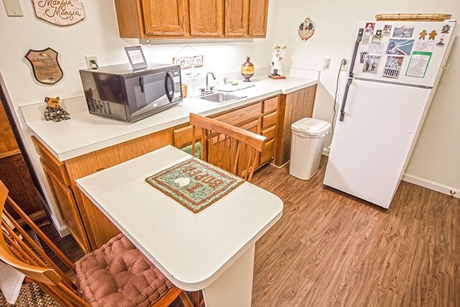 A cozy kitchen with wooden cabinets, a small dining table, and appliances.