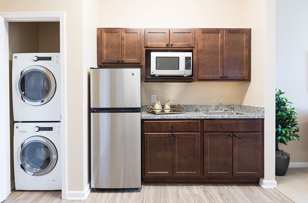 A modern kitchen with wooden cabinets, a stainless steel refrigerator, and a microwave.