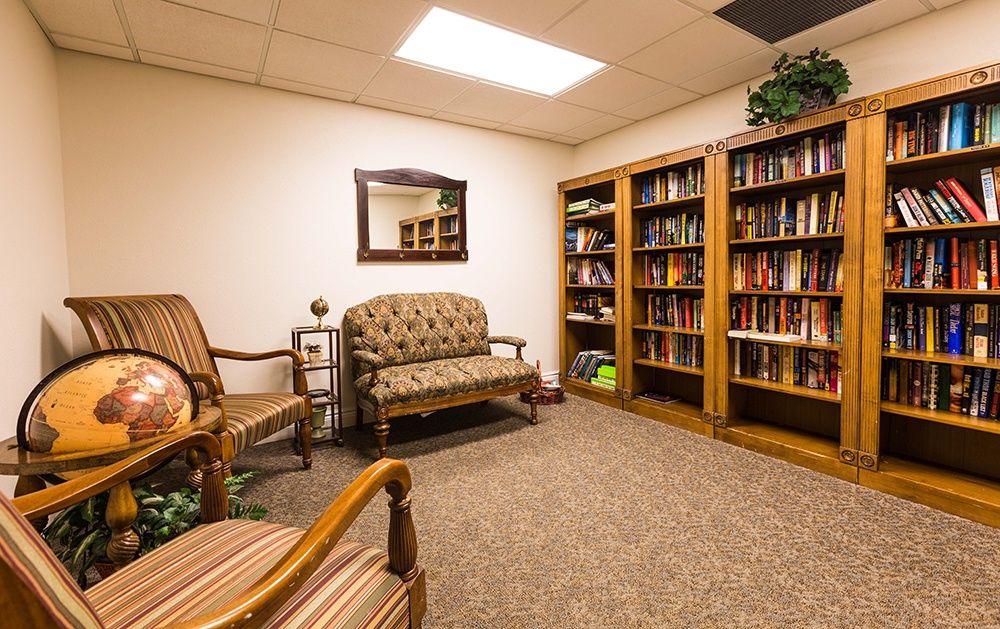 A cozy library room with bookshelves, a mirror, and comfortable seating.
