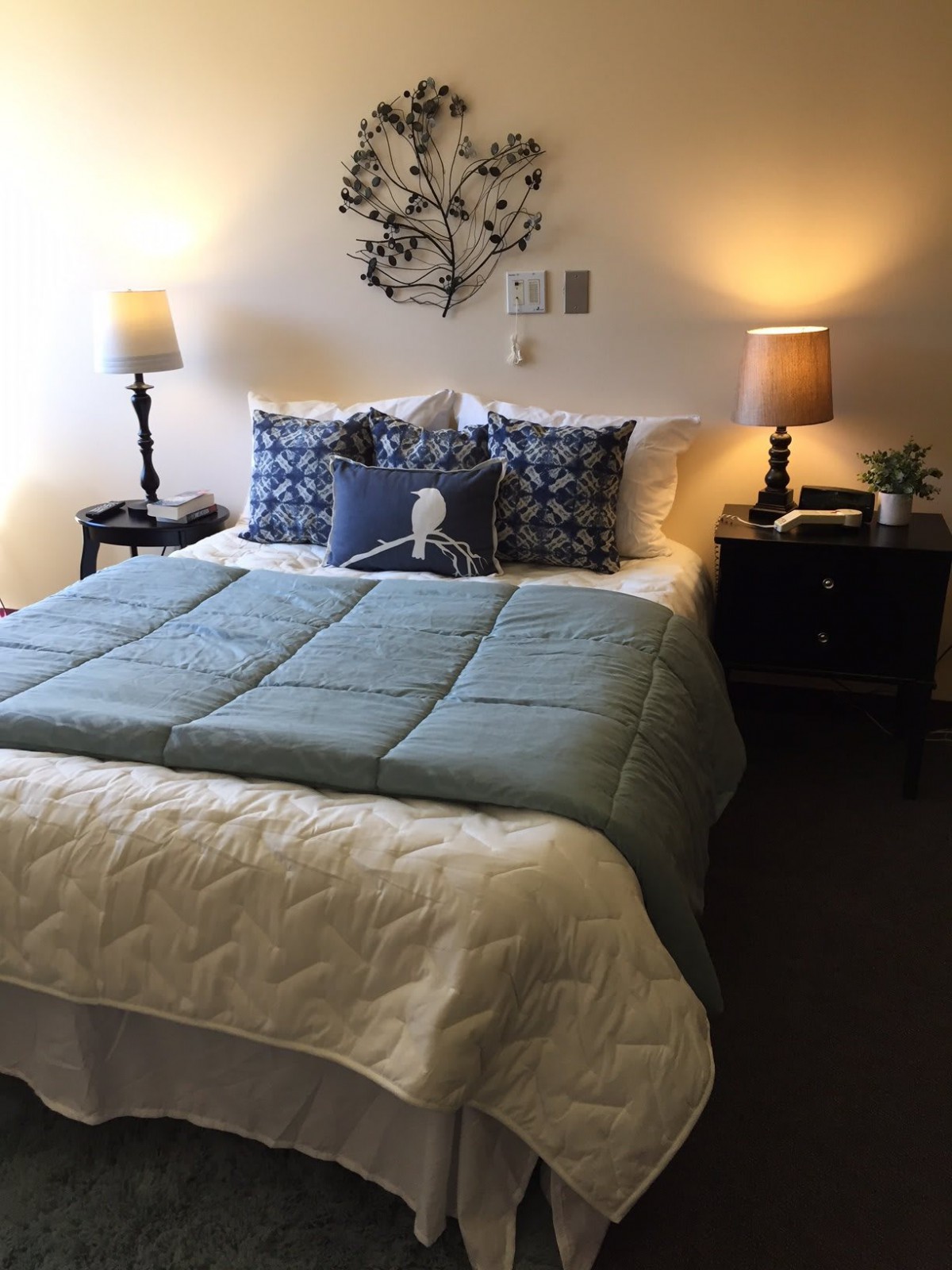 A cozy bedroom with a neatly made bed, flanked by two nightstands and lamps.
