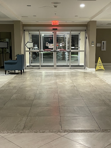 A view of the hotel lobby showcasing the entrance doors, a seating area, and a caution sign on the floor.