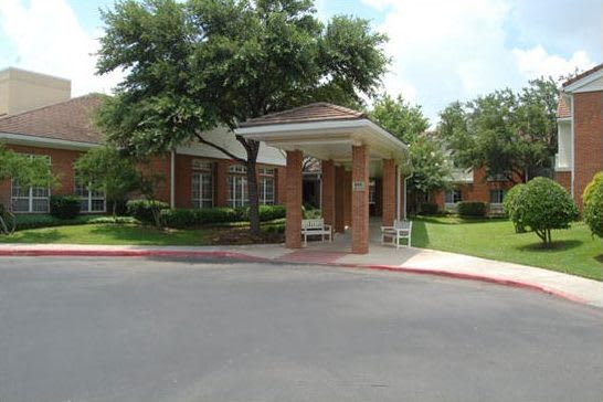 A brick building entrance with surrounding greenery and trees.