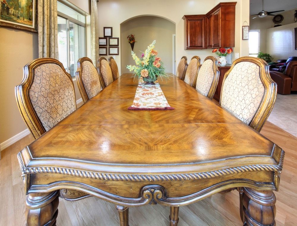 A spacious dining room with a large wooden table and ornate chairs.