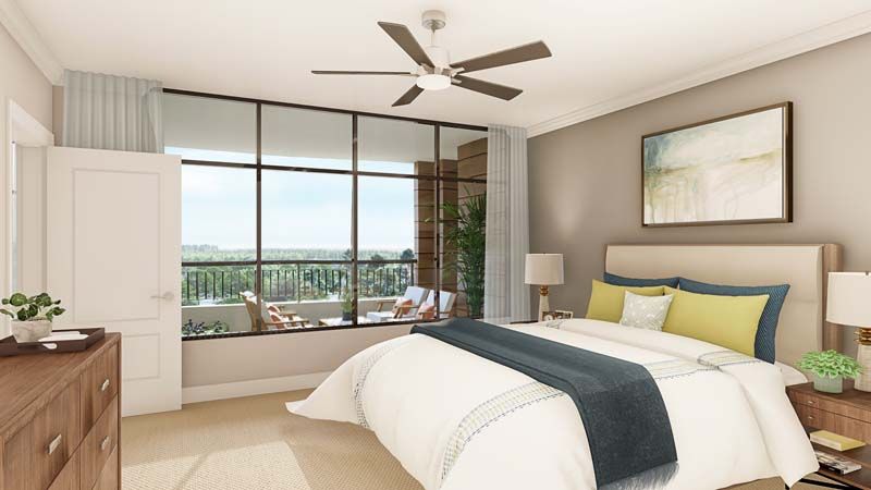 A modern bedroom with large windows, featuring neutral tones and a ceiling fan.