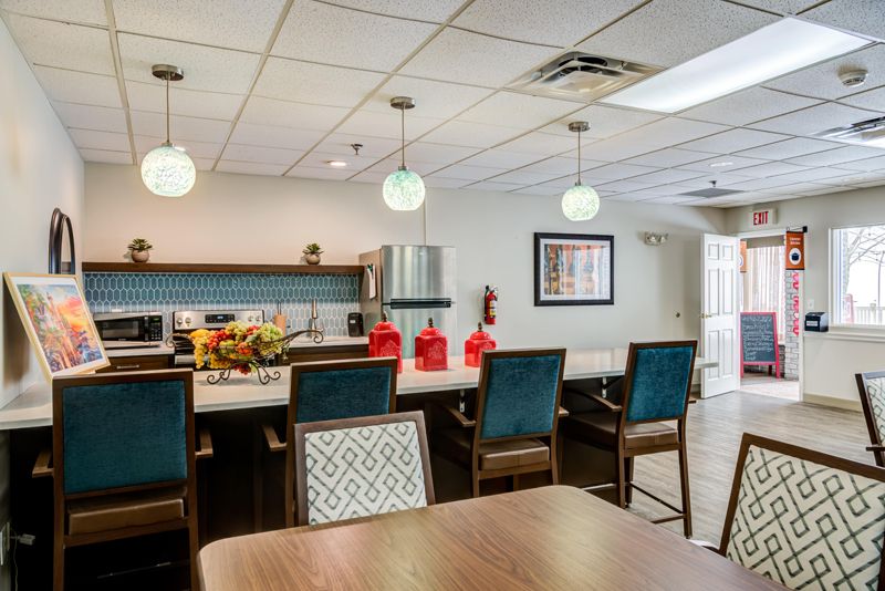 A modern kitchen and dining area with pendant lighting and colorful chairs.