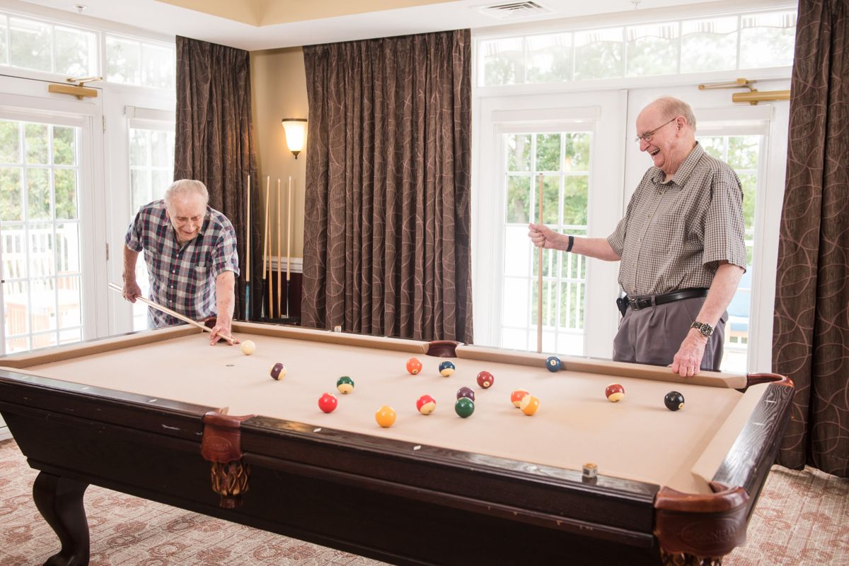 Two seniors enjoying a game of billiards in a cozy indoor setting.
